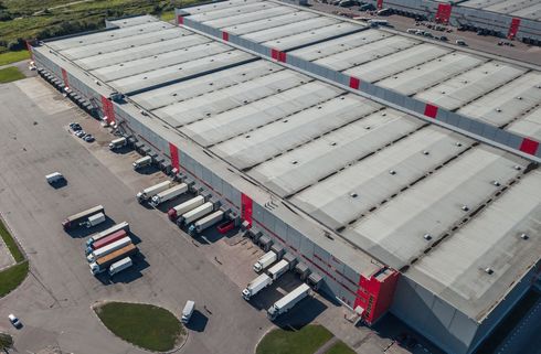 An aerial view of a large warehouse with trucks parked in front of it.