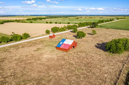 An aerial view of a red barn with a texas flag painted on it.