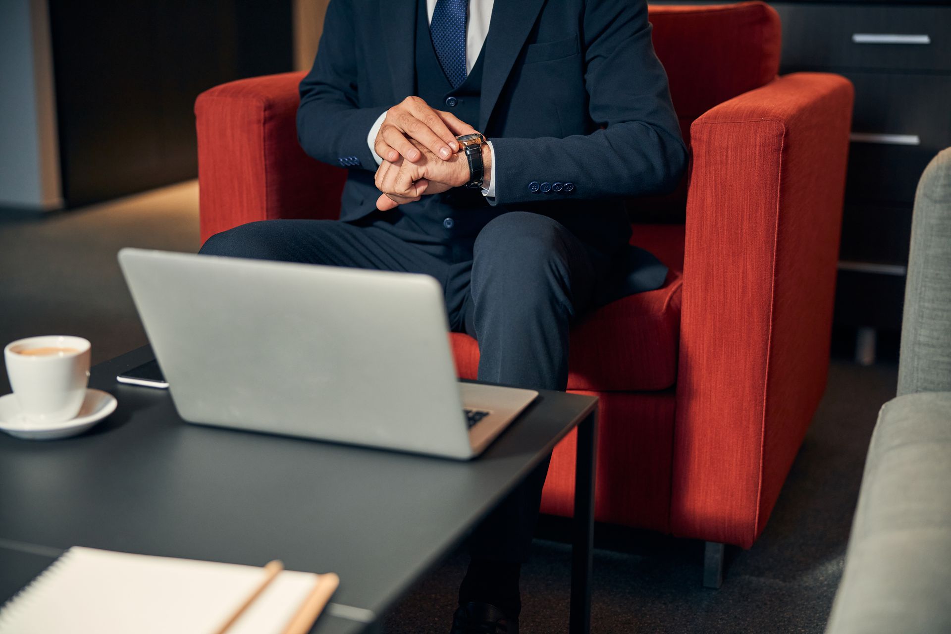 A man in a suit is sitting in a chair using a laptop computer.