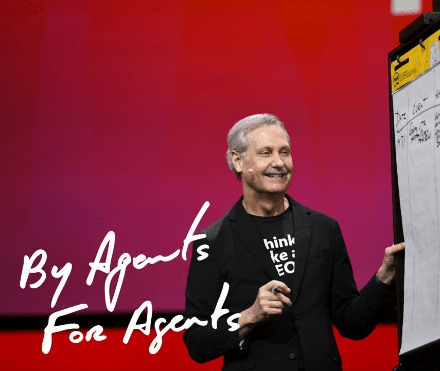 A man is standing in front of a white board with the words by agents for agents written on it