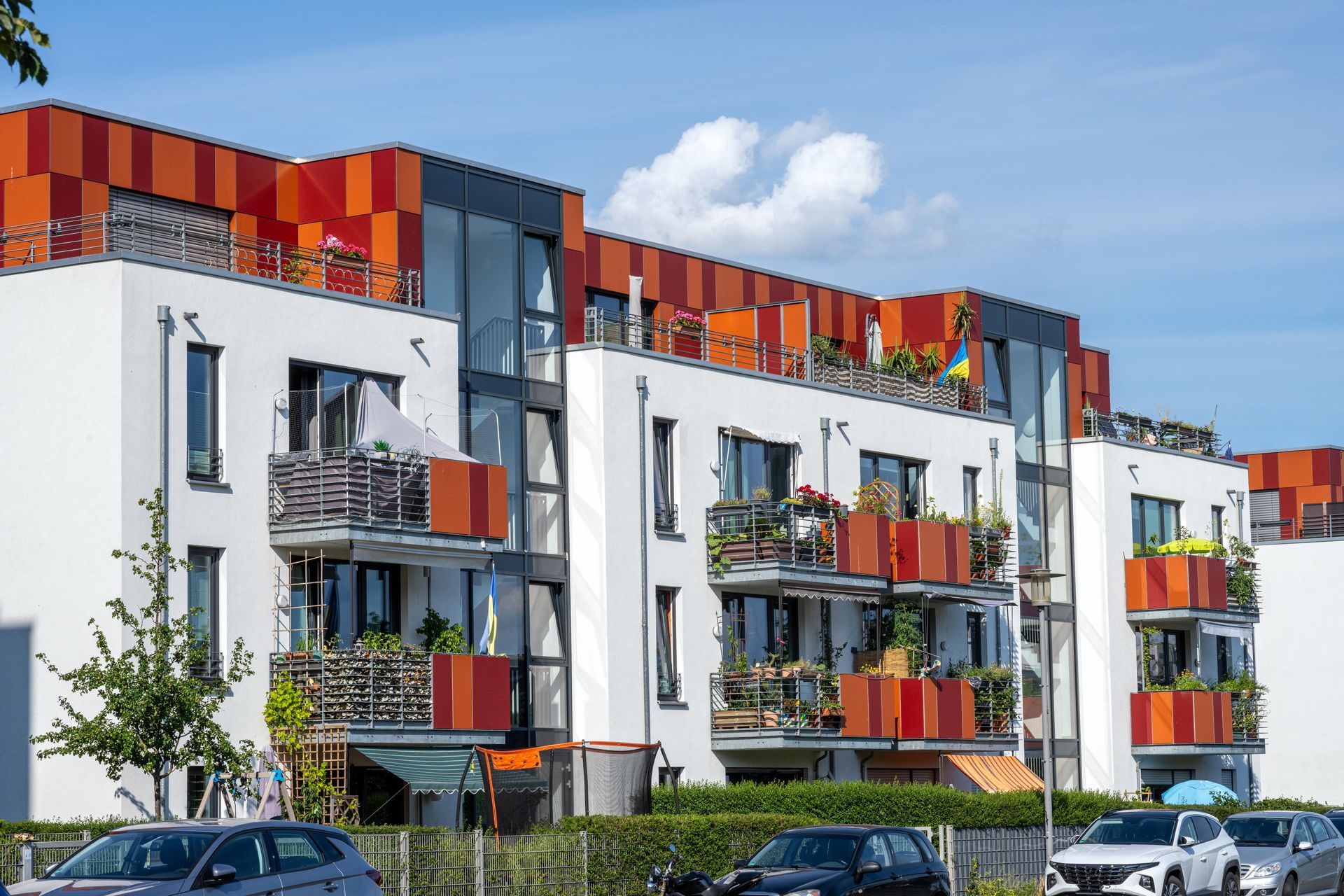 A row of apartment buildings with cars parked in front of them.