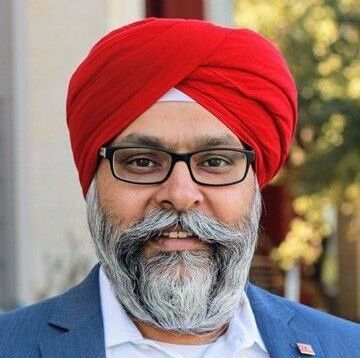 A man with a beard and glasses is wearing a red turban.