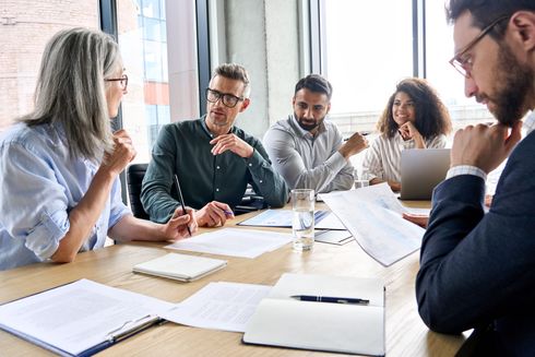 A group of people are sitting around a table having a meeting.