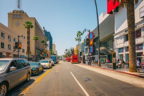 A busy street in hollywood with cars parked on the side of the road.