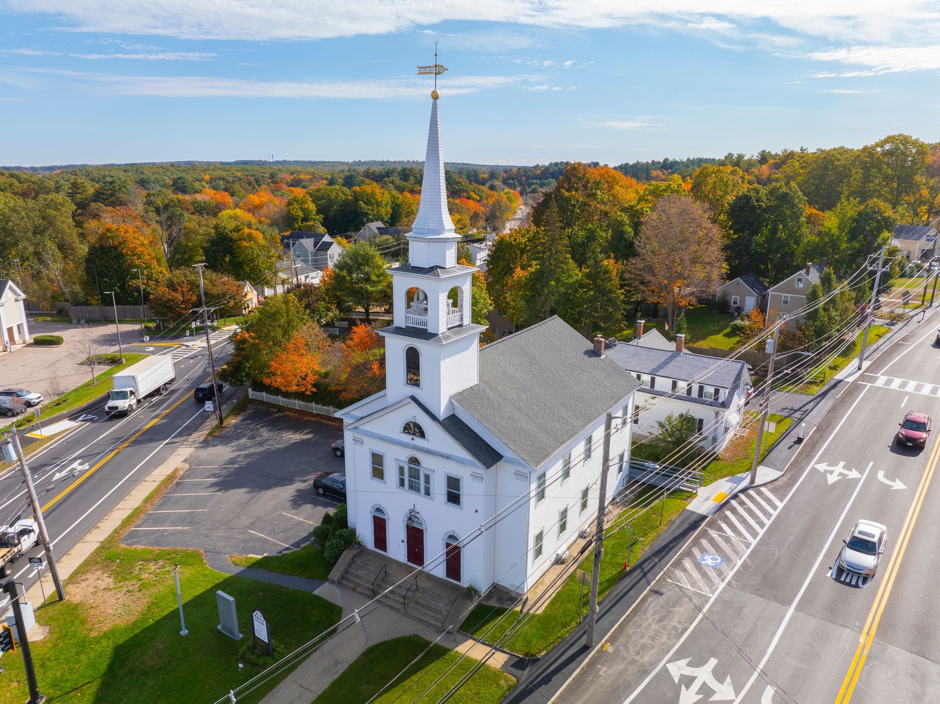 An aerial view of a church surrounded by trees and a highway.