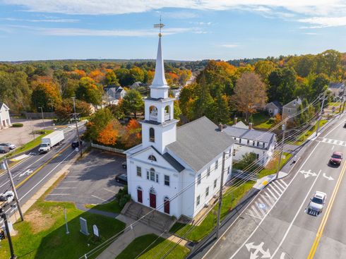 An aerial view of a church surrounded by trees and a highway.