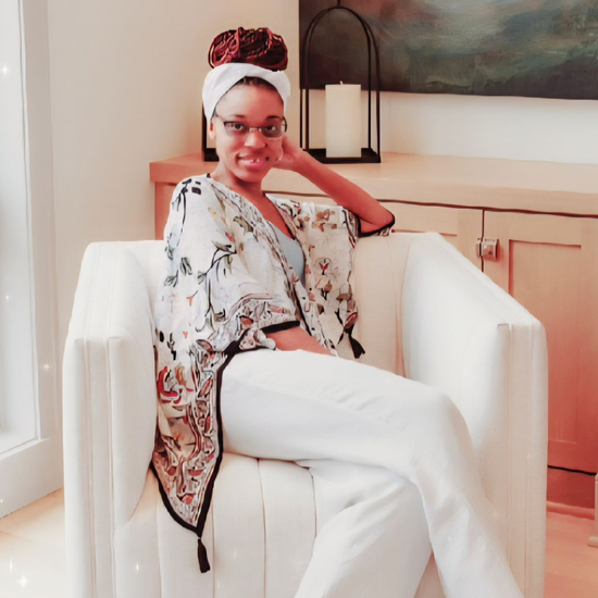 A woman is sitting at a desk with a laptop and a vase of flowers.
