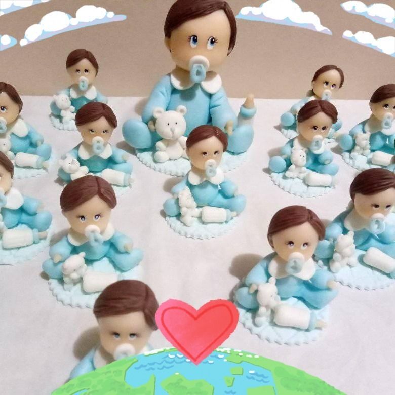 Bebés de fondant con trajes azules y chupetes, sobre pequeñas plataformas, con un corazón y un globo terráqueo.