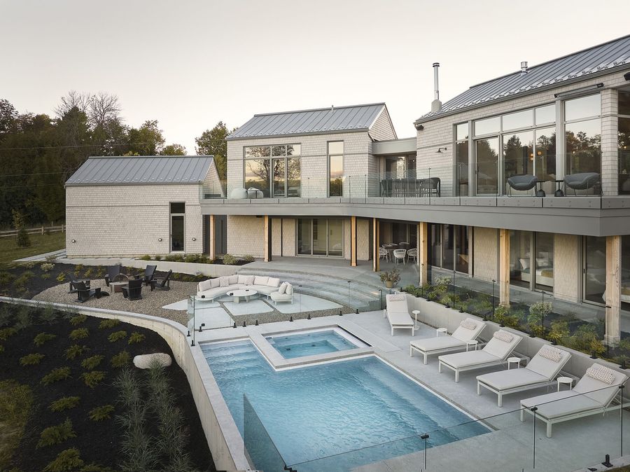 Maison moderne à la façade texturée, garage et touches sombres, nichée dans une forêt luxuriante.