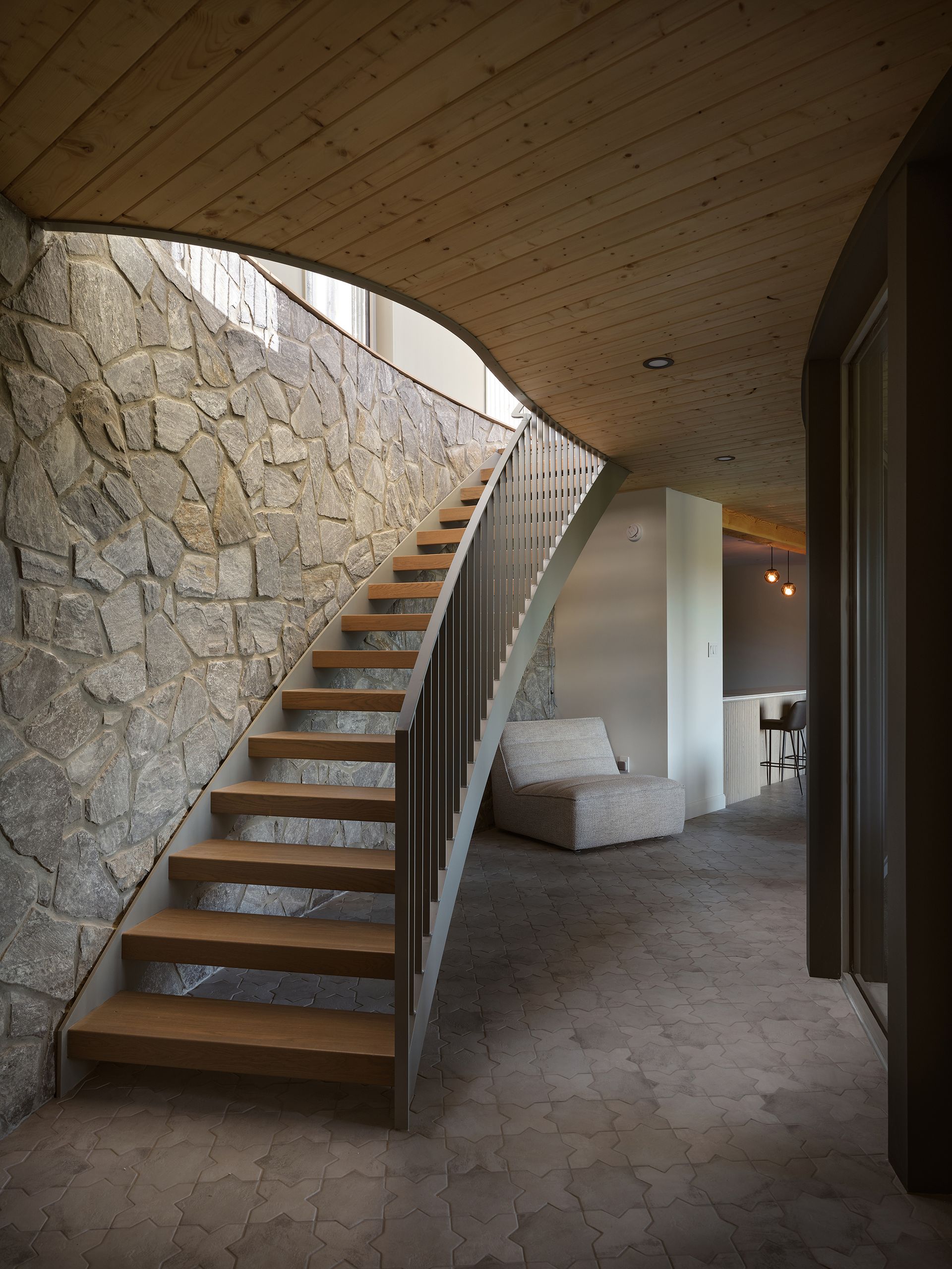 Escalier en pierre avec marches et rampe en bois menant à l'étage.