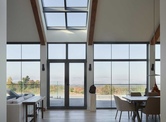 Intérieur moderne avec murs blancs, étagères intégrées, escalier et luminaire suspendu.