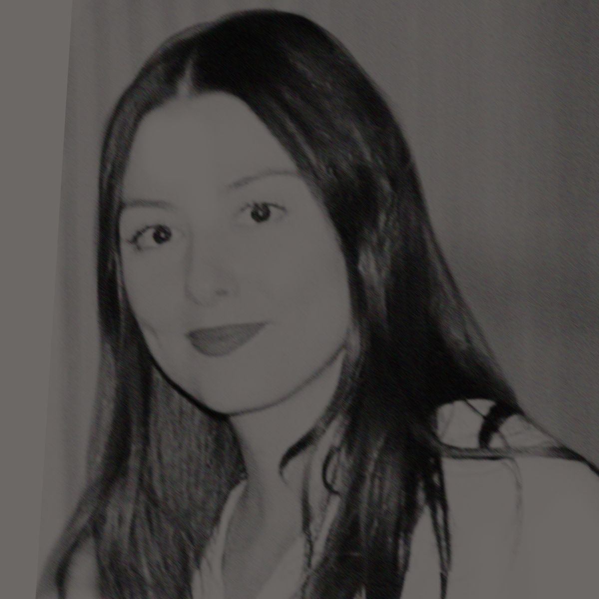 Femme aux longs cheveux bruns, rouge à lèvres rouge, souriante, vêtue d'une chemise blanche ; sur un fond flou.