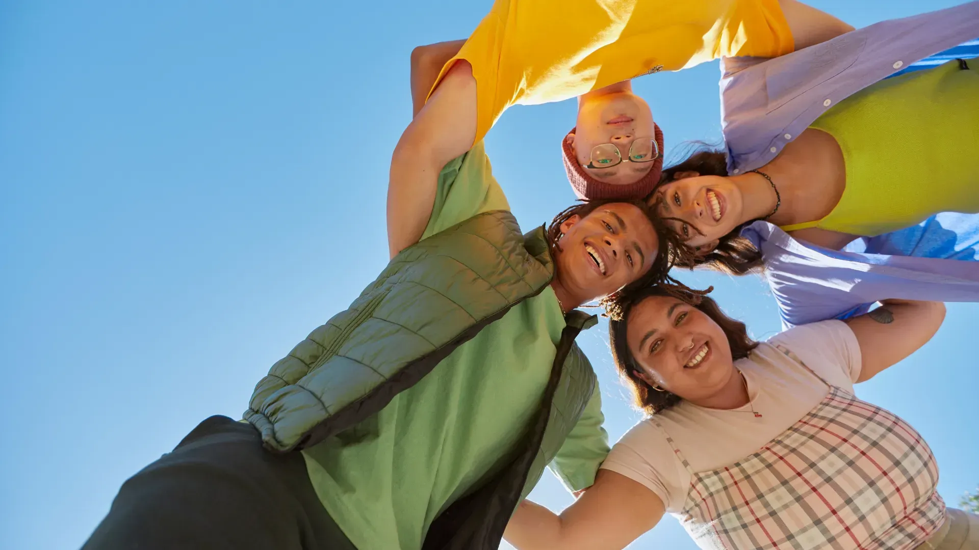 A group of people are standing in a circle holding hands and smiling.