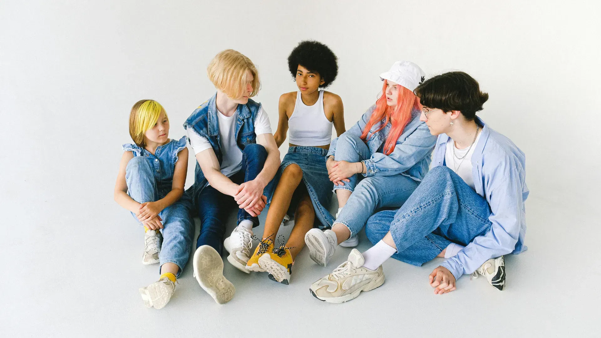 A group of young people are sitting on the floor talking to each other.
