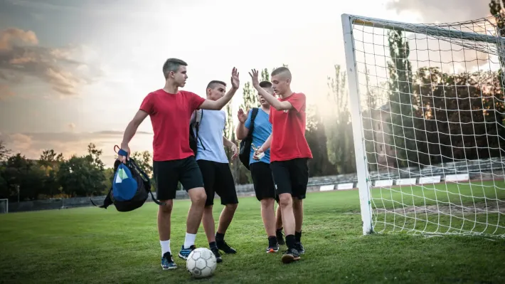 A group of young men are standing on a soccer field giving each other a high five.