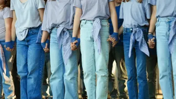 A group of people wearing blue jeans are standing next to each other.