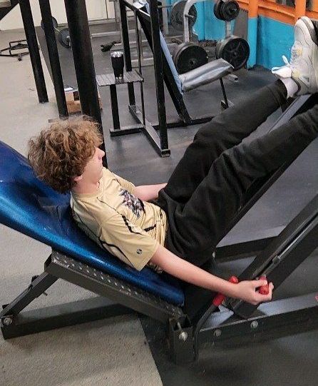 A man is doing push ups in a gym in front of a laptop.
