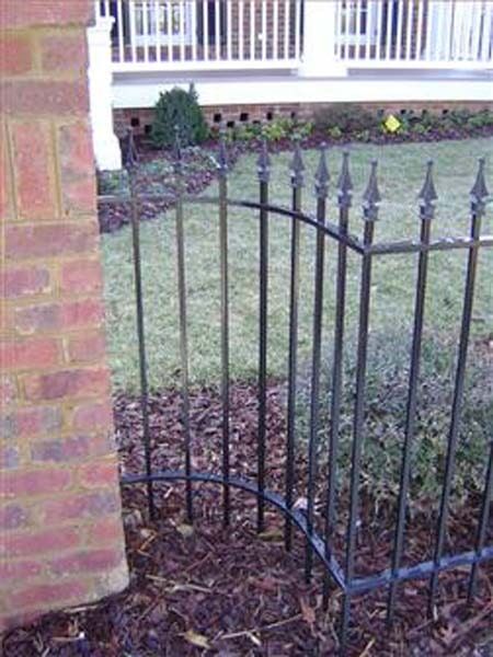 Installation of Fences — Curved Fence Beside a Brick Wall in Winston-Salem, NC