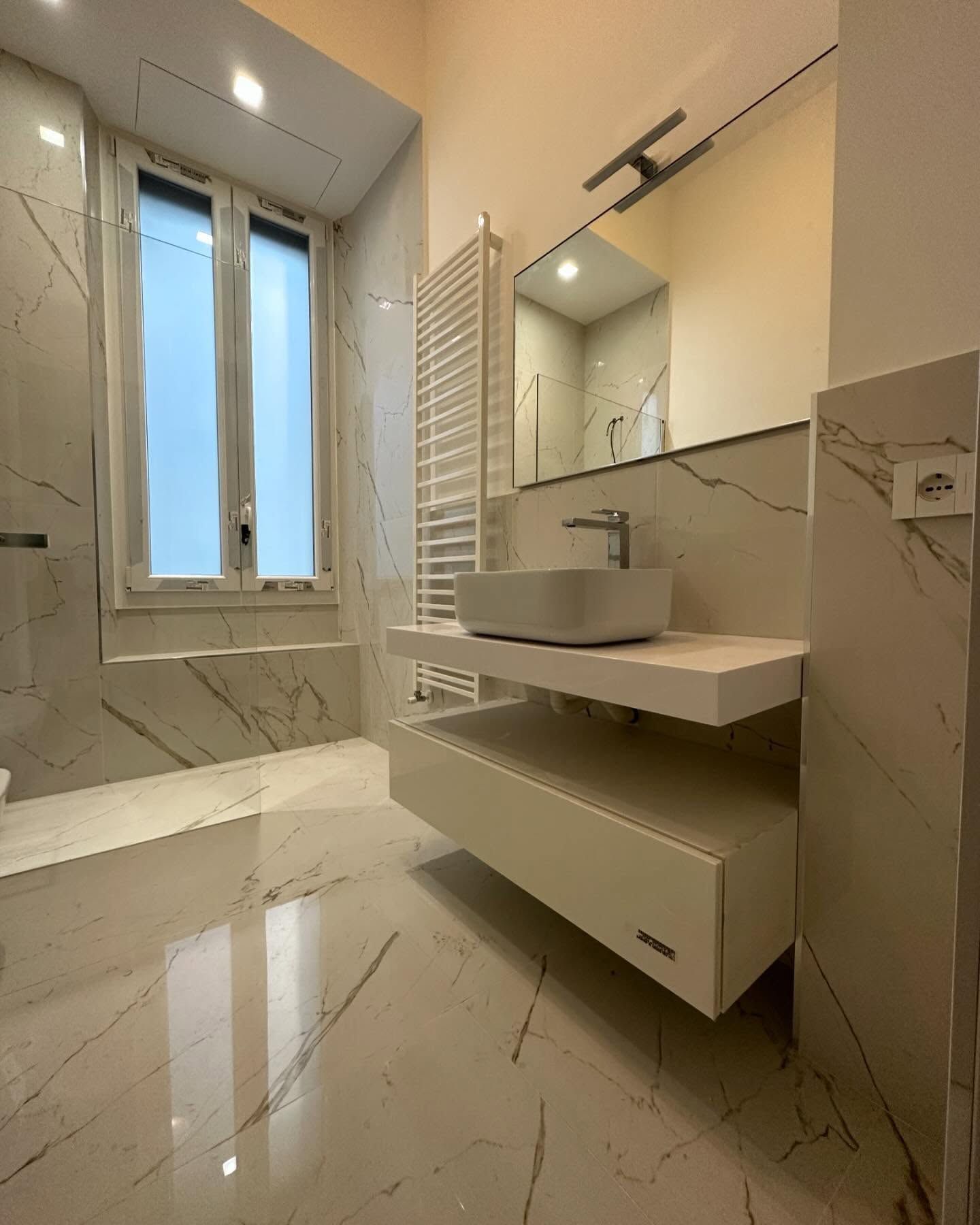 Un bagno con lavandino, specchio e finestra.