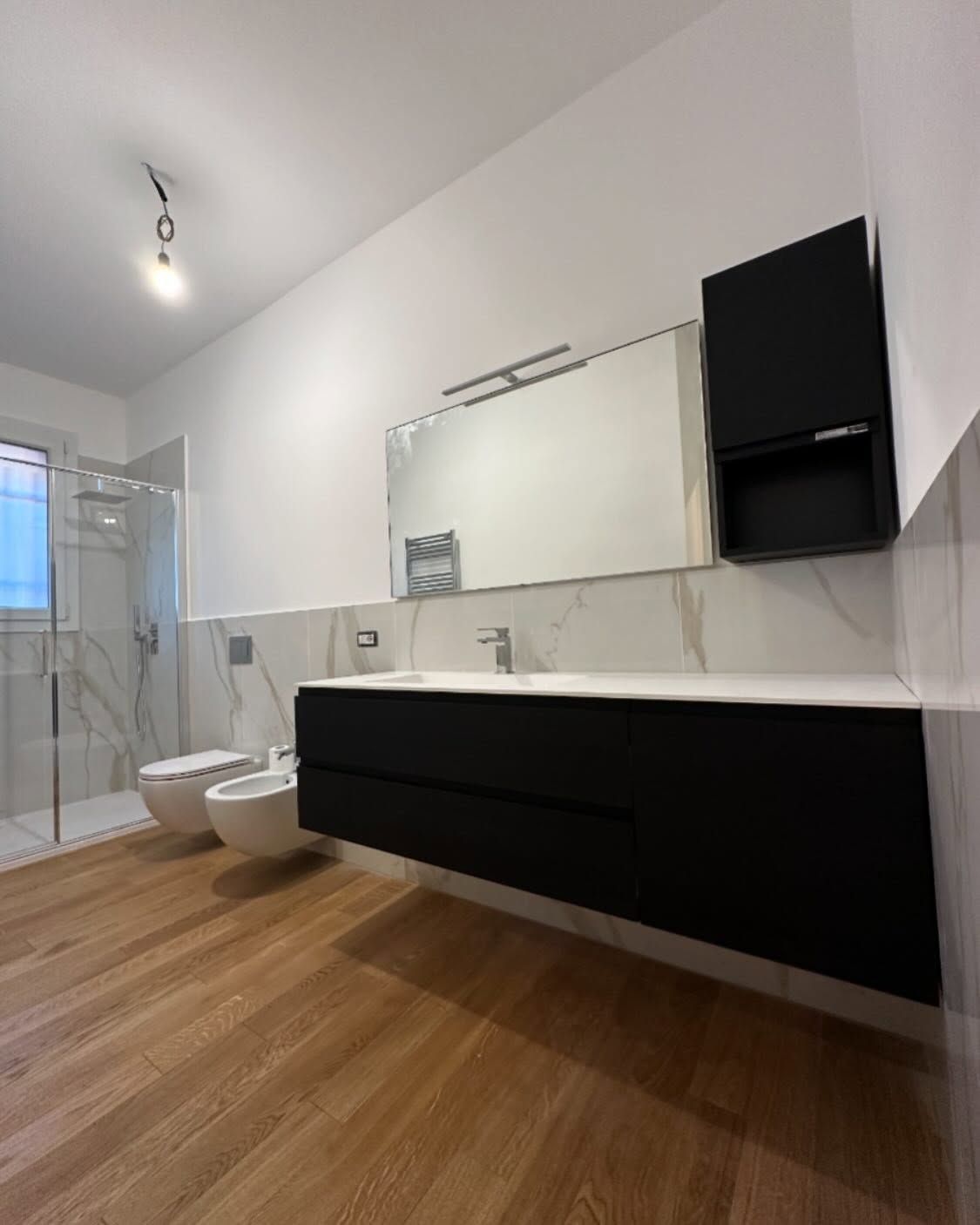 Un bagno con due water, un lavandino e uno specchio.