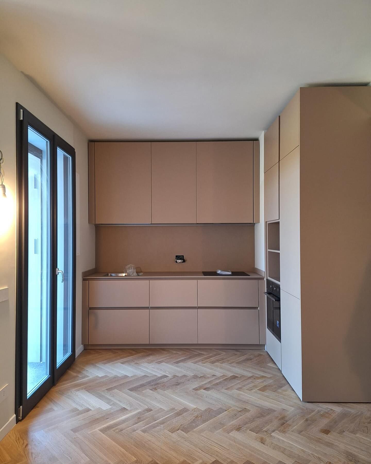 Una cucina con pavimento a spina di pesce e porte scorrevoli in vetro