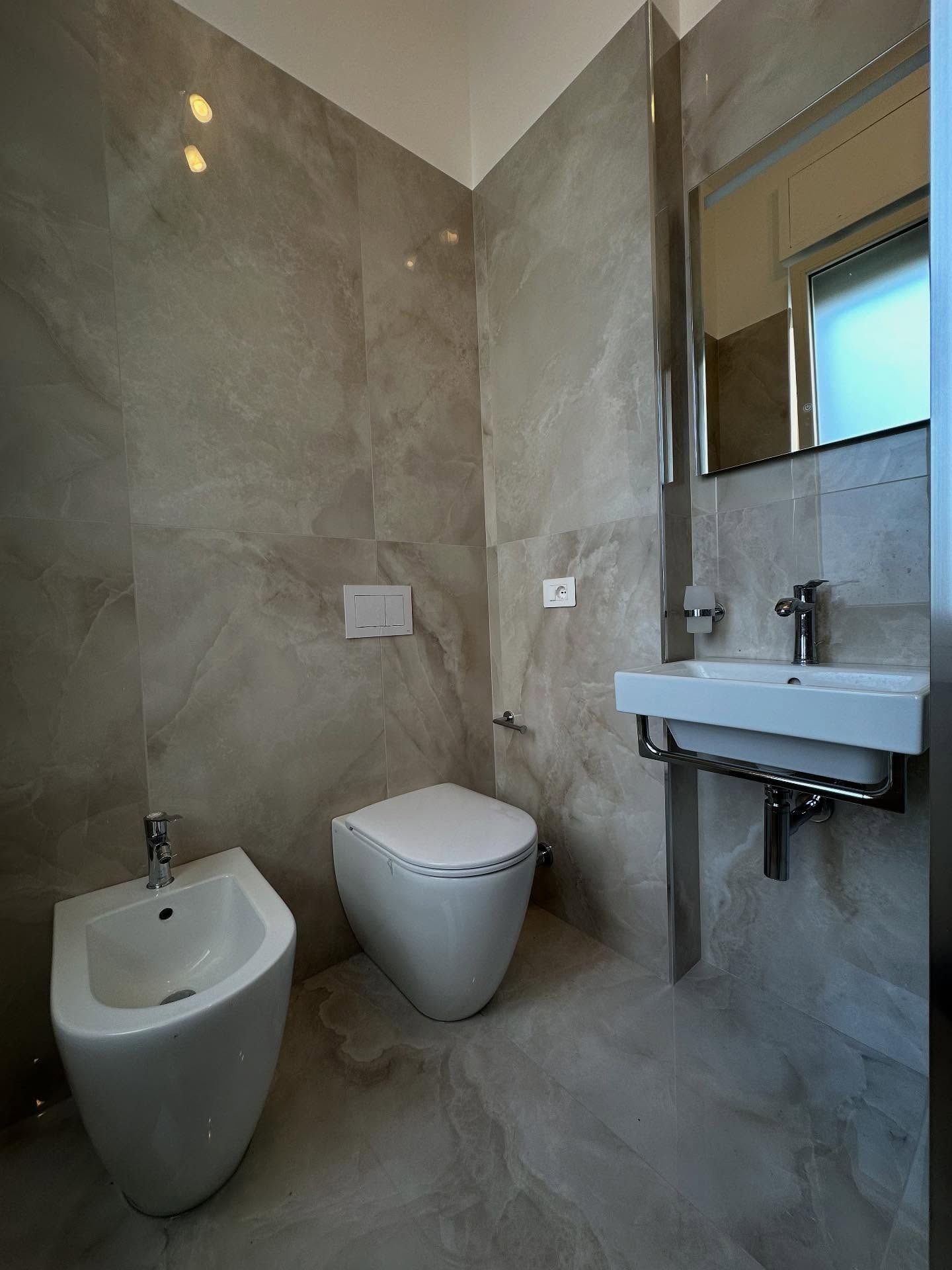 Un bagno con wc, bidet, lavandino e specchio.