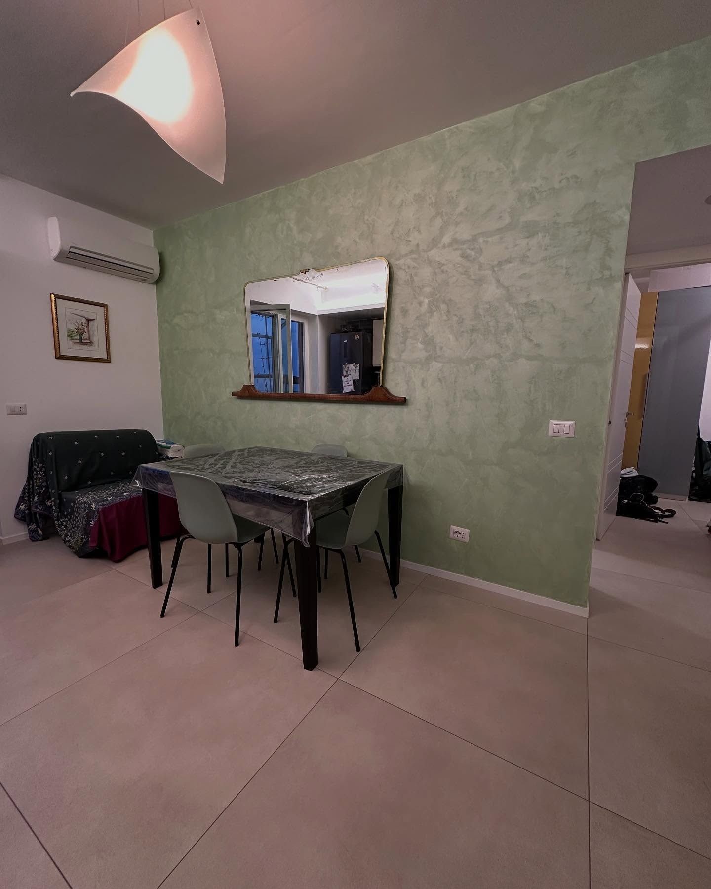 Un soggiorno con un tavolo, delle sedie e uno specchio alla parete.