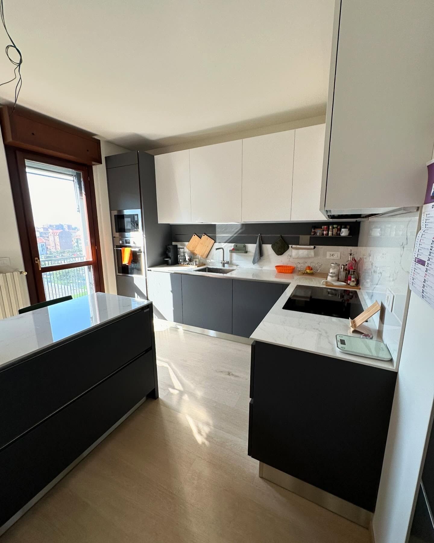 Una cucina con mobili neri e ripiani bianchi e una grande isola al centro.