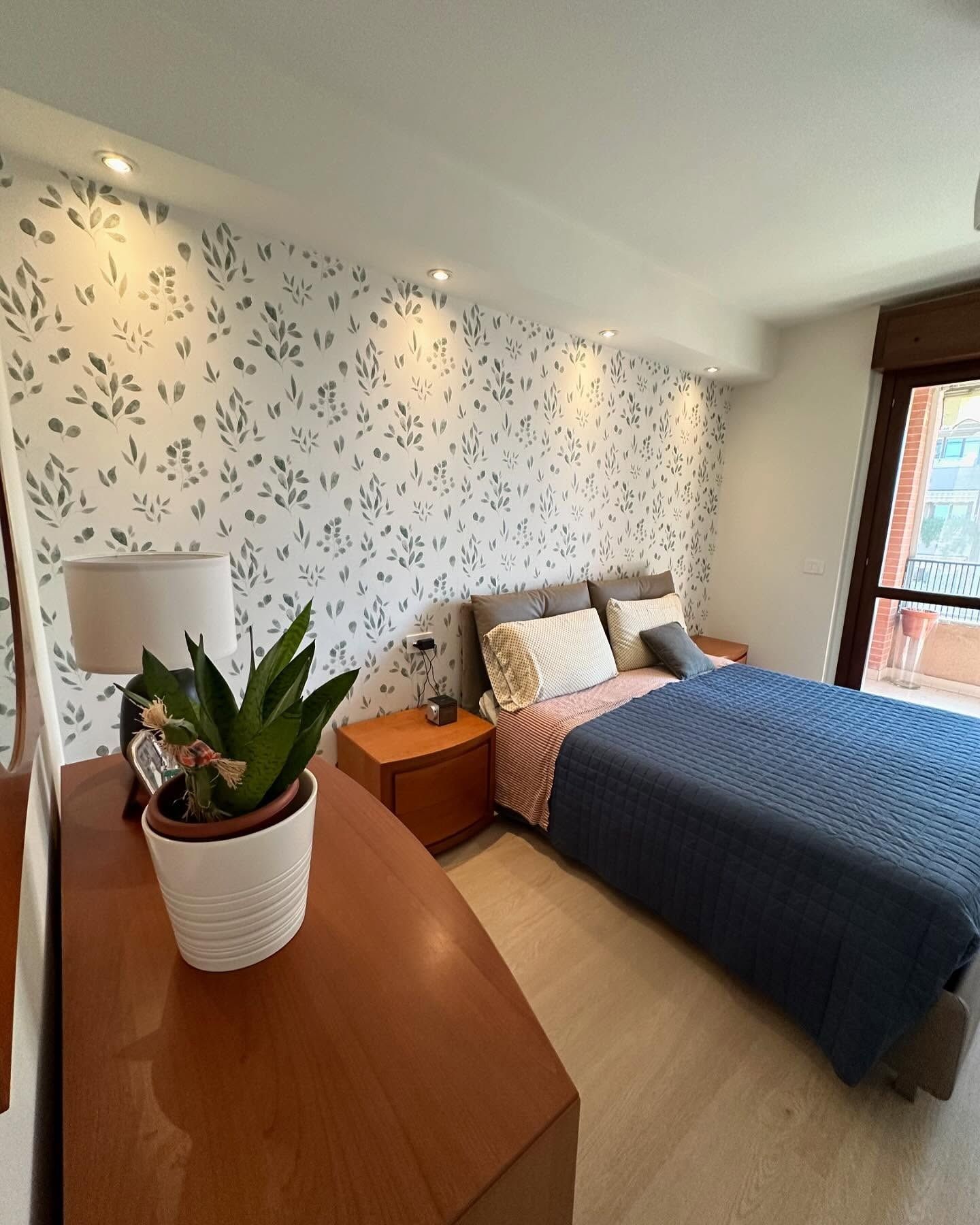 Una camera da letto con un letto grande e una pianta in vaso sul comò