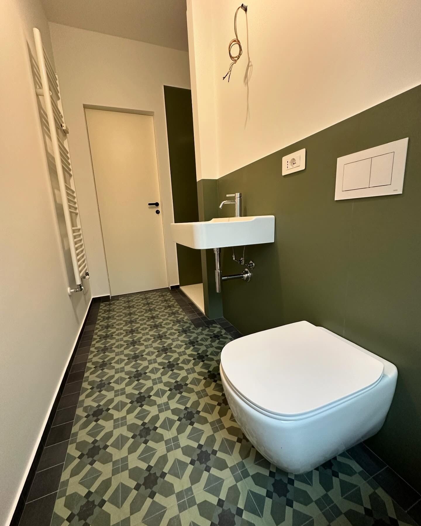 Un bagno con wc, lavandino e pareti verdi