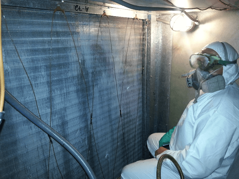 a man wearing a gas mask and goggles is sitting in front of a coil condenser