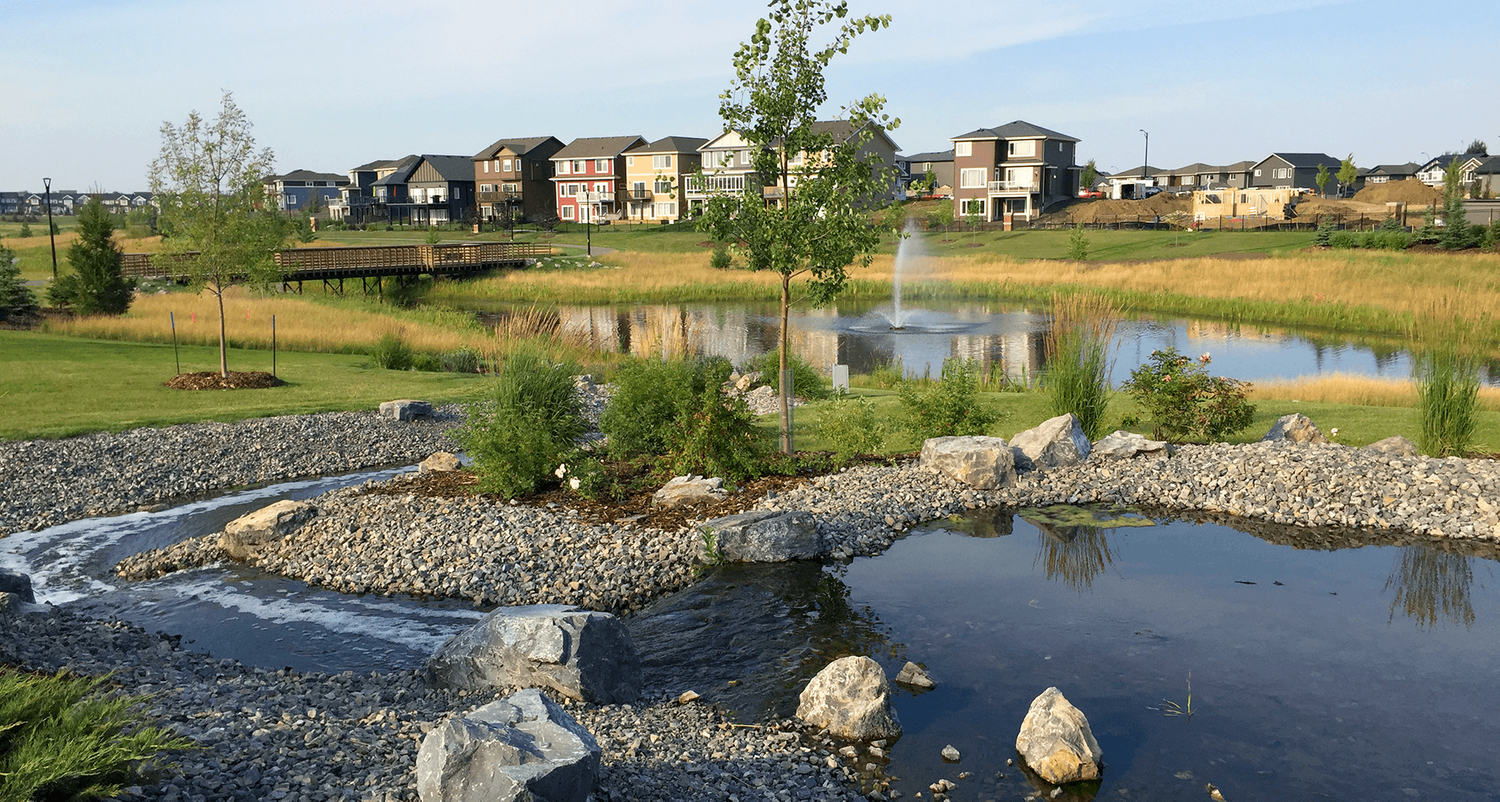 A pond with a fountain in the middle of it in a park.
