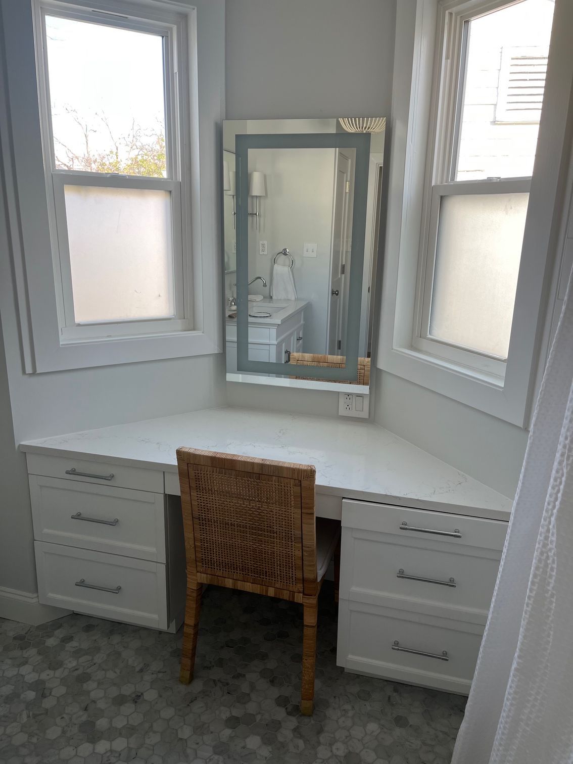 There is a desk with a chair and a mirror in the corner of the room.