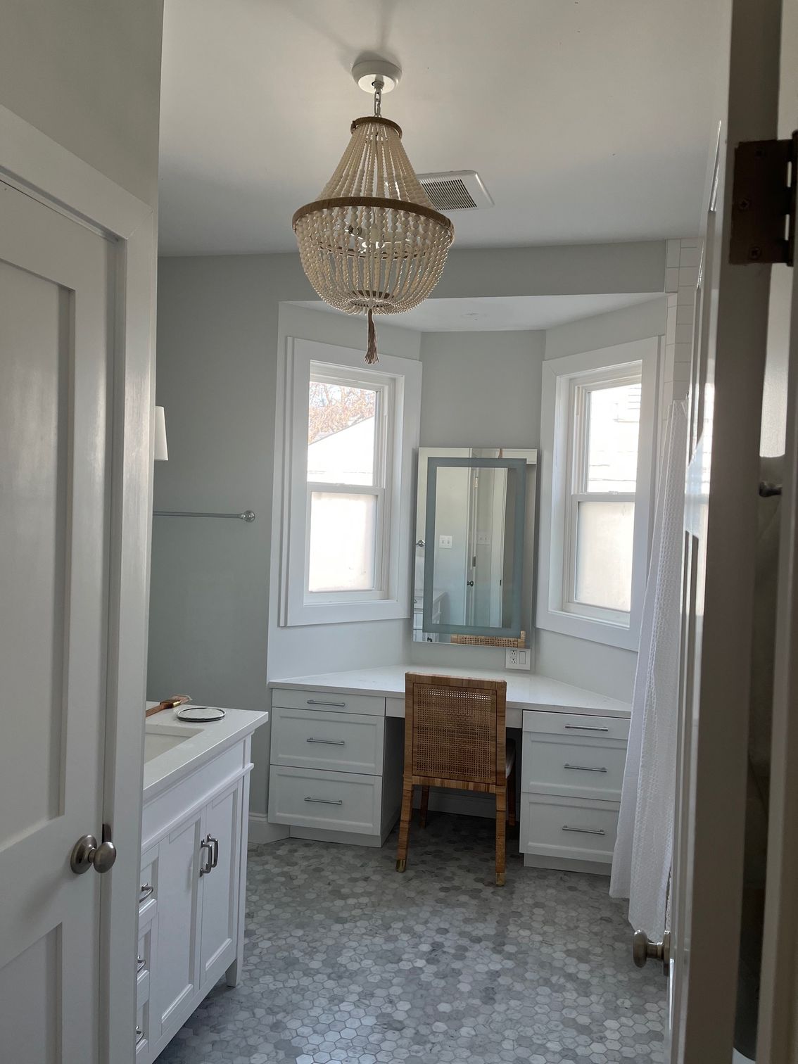A bathroom with a vanity , desk , mirror and chandelier.