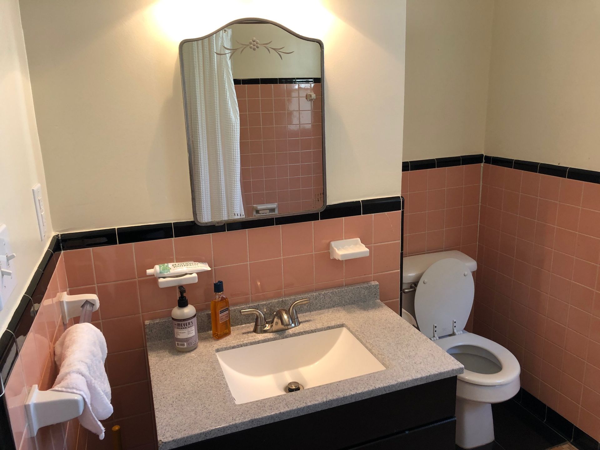 A bathroom with pink tiles and a sink and toilet