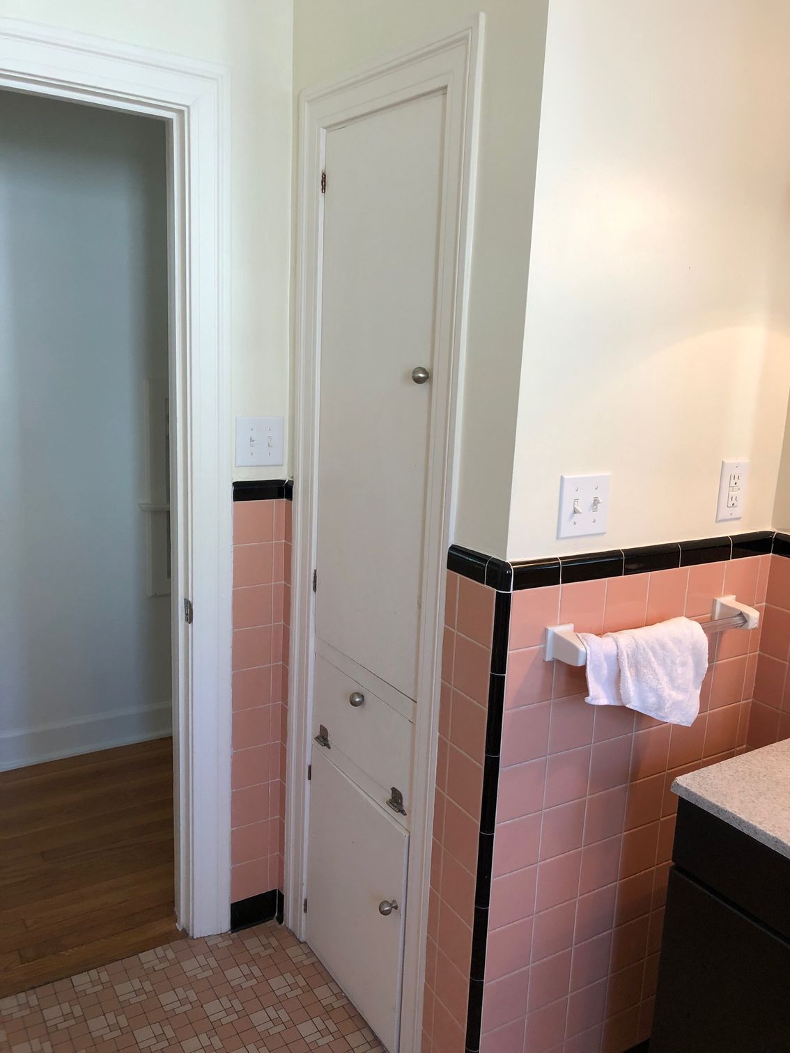 A bathroom with pink tiles and a white cabinet