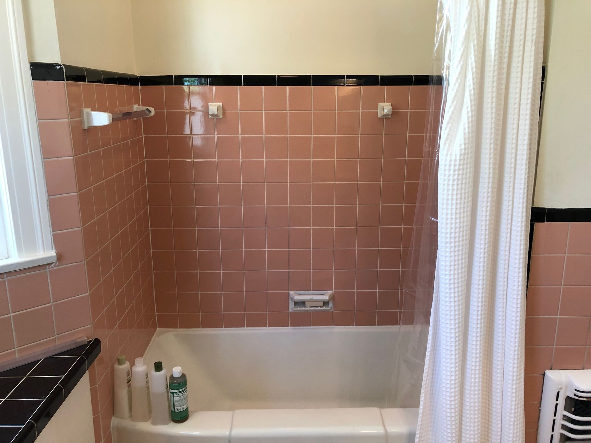 A bathroom with pink tiles and a bathtub