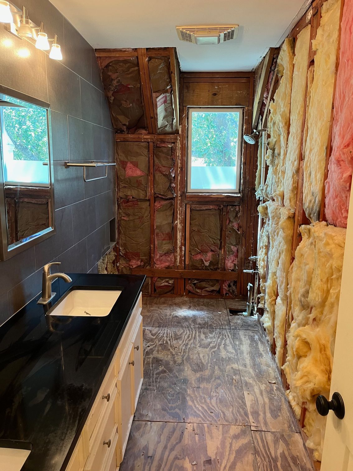 A bathroom with a sink , mirror , and insulation on the walls.