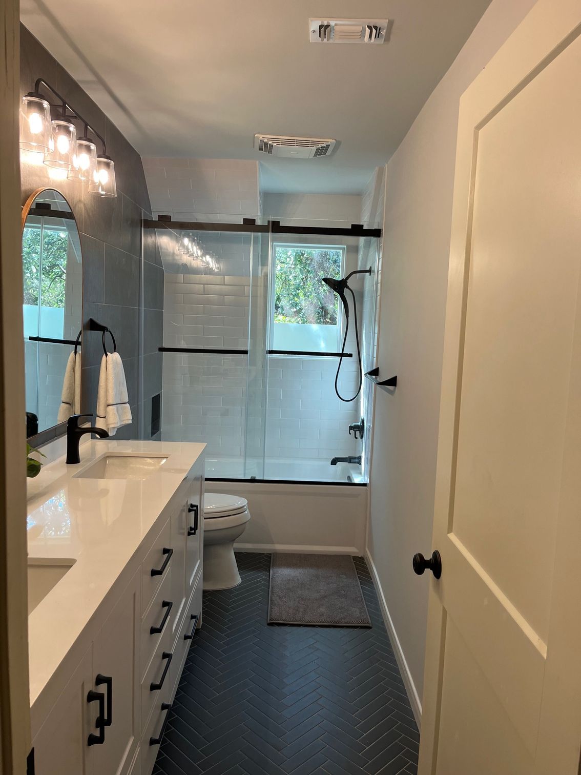 A bathroom with a sink , toilet , shower and mirror.
