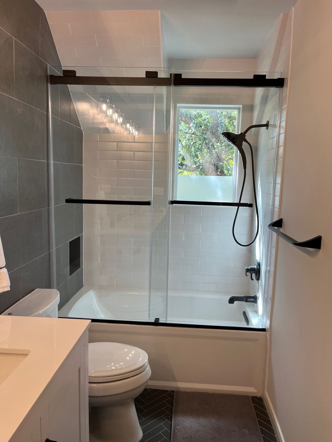 A bathroom with a toilet , tub , shower and window.