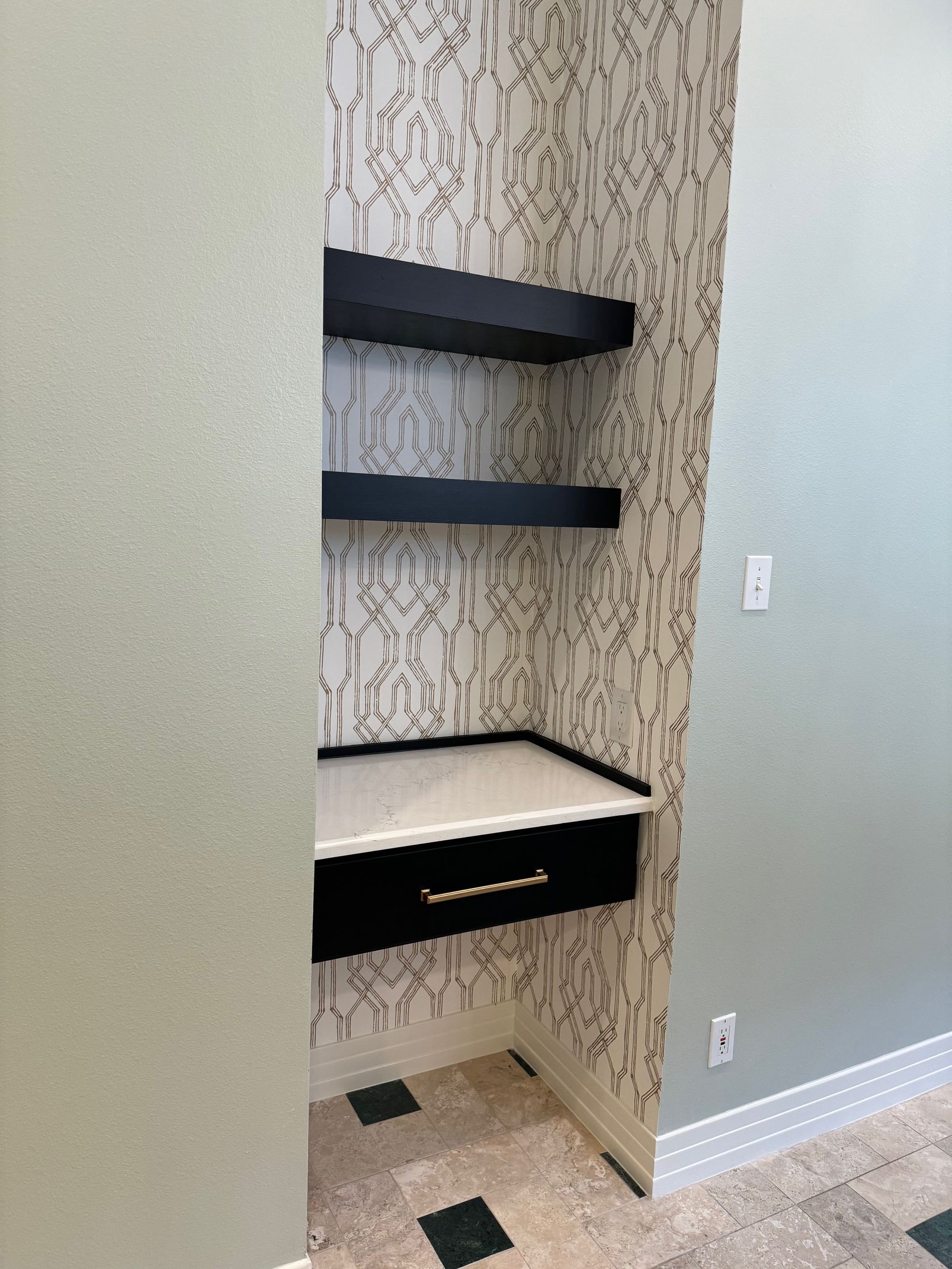 A corner of a room with a desk and shelves.