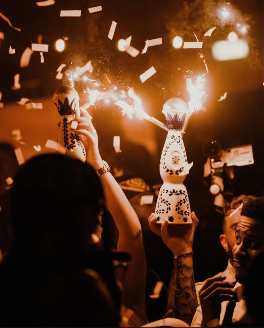 People holding up bottles with sparklers amid confetti.