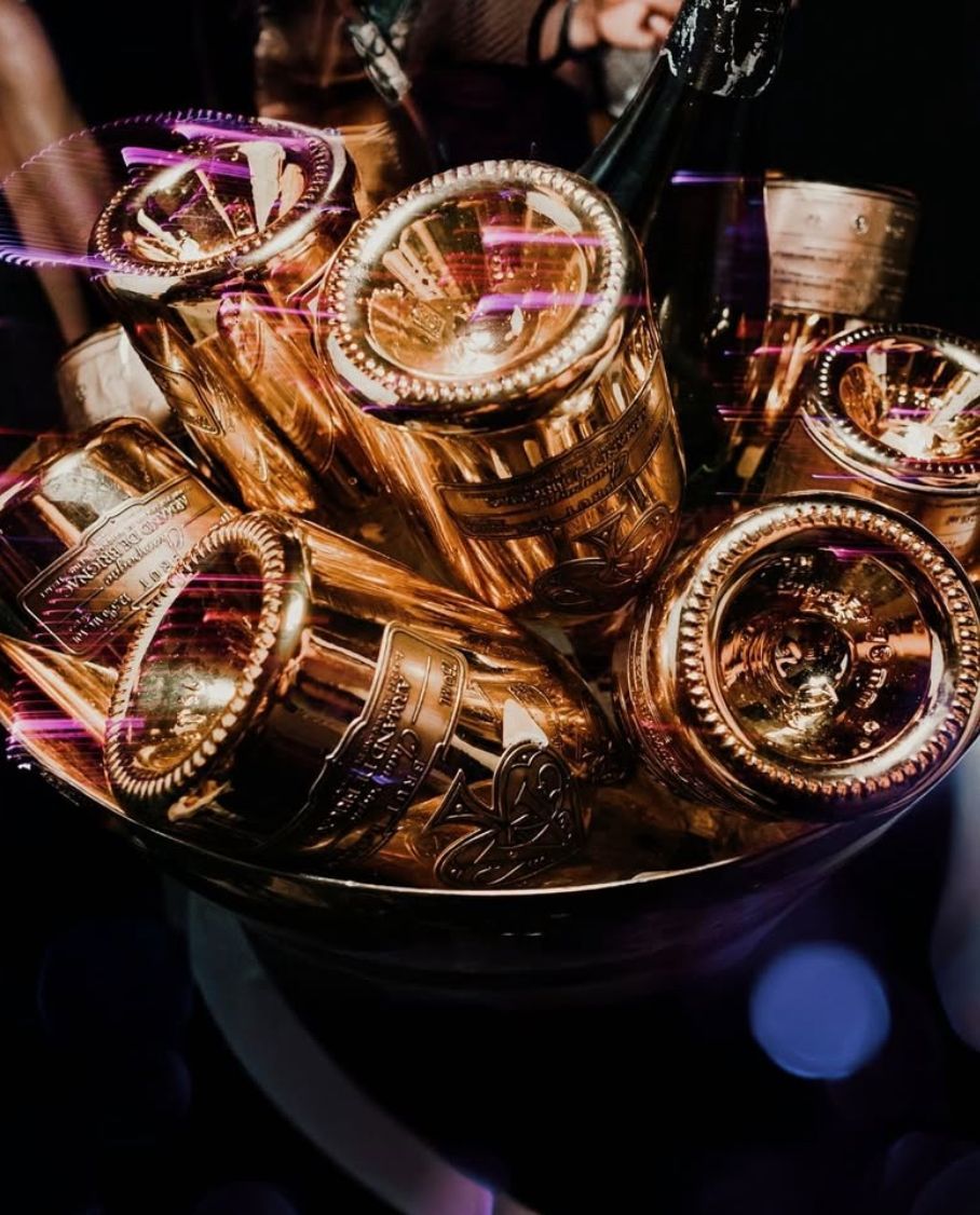 Golden champagne bottles in an ice bucket, with blurred background lights.
