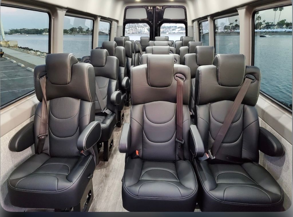 Burgundy Rolls-Royce sedan with white-wall tires, illuminated headlights, parked at night.