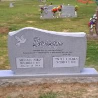 Gray gravestone with name Benton and two memorial plaques in a cemetery