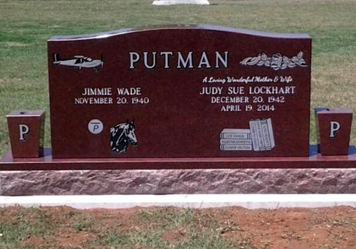 Red granite Putman family gravestone with military emblems and engraved names in a cemetery