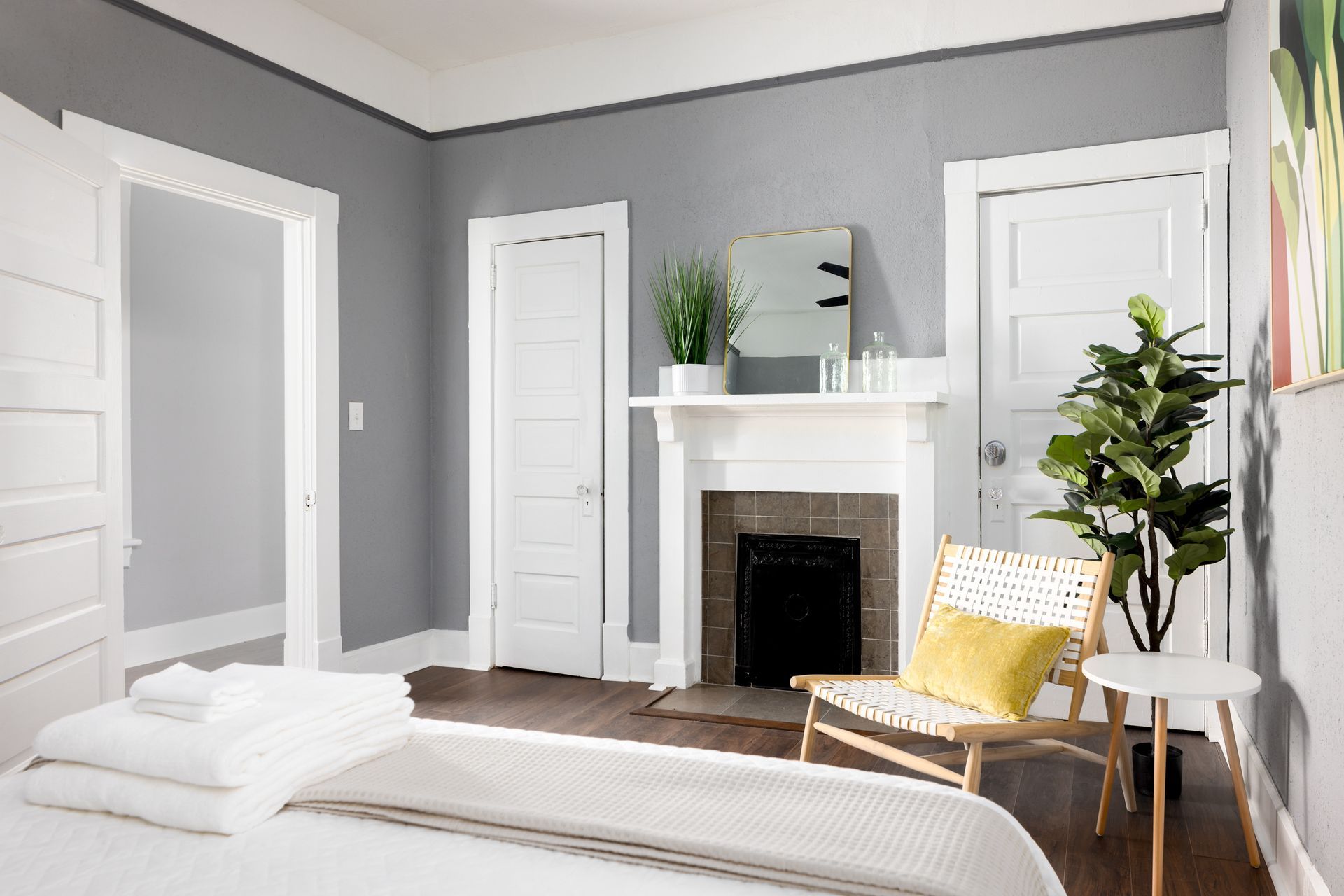 A bedroom with a bed , chair , fireplace and mirror.
