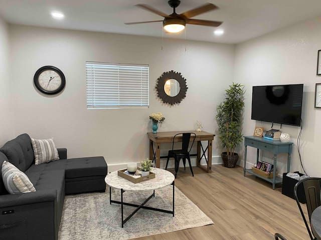 A living room with a couch , table , television and ceiling fan.