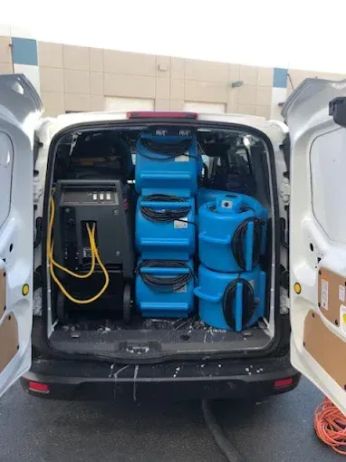 White van open to reveal water damage restoration equipment: dehumidifiers and air movers.
