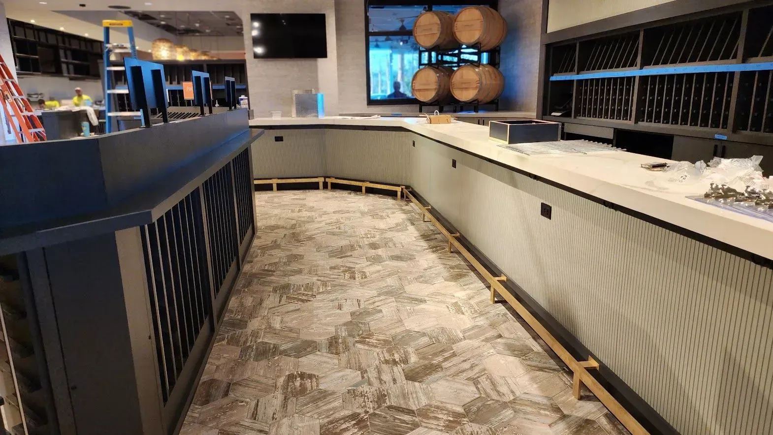 A long narrow room with a bar and barrels on the wall.